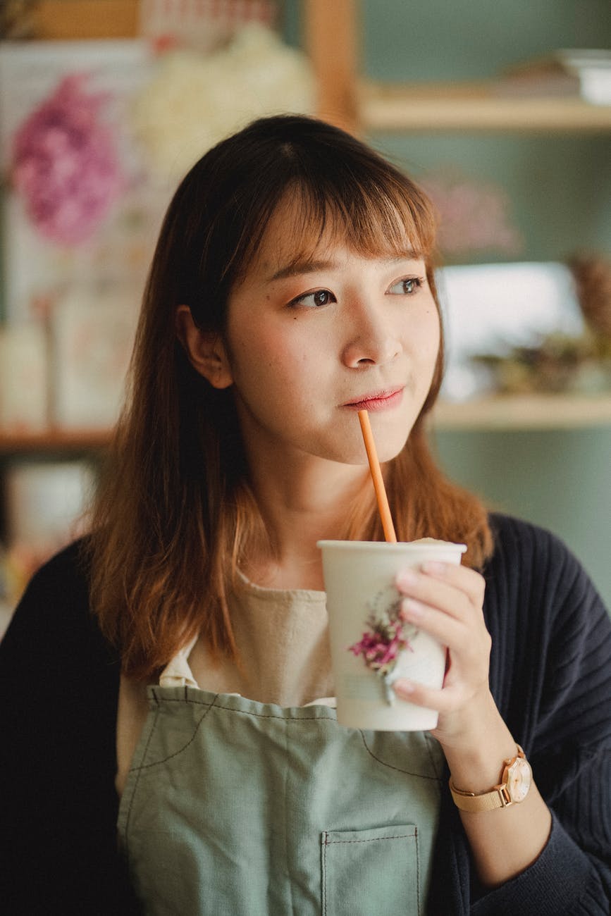 dreamy female with hot drink in paper cup