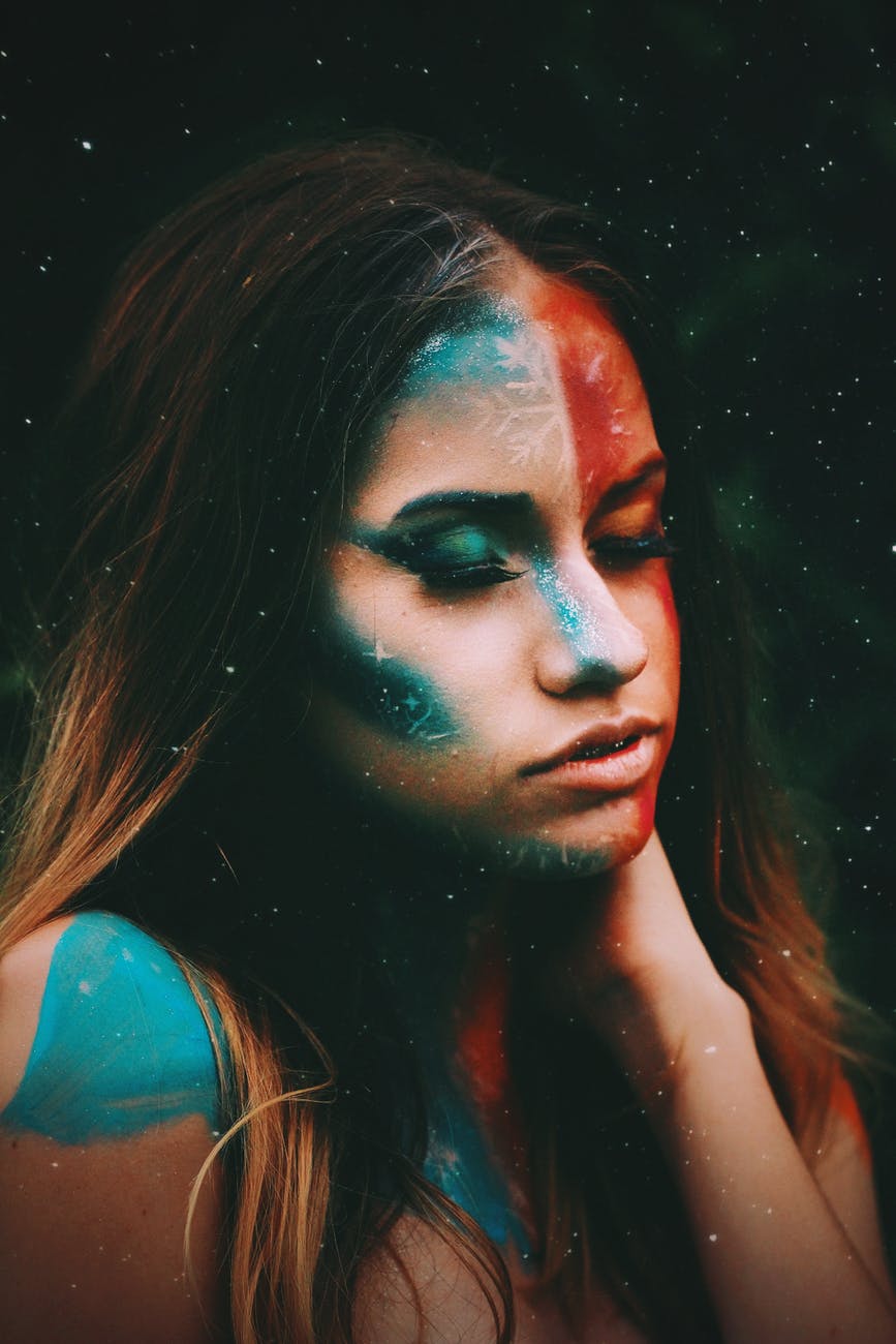 calm woman with bright painted face sitting with closed eyes