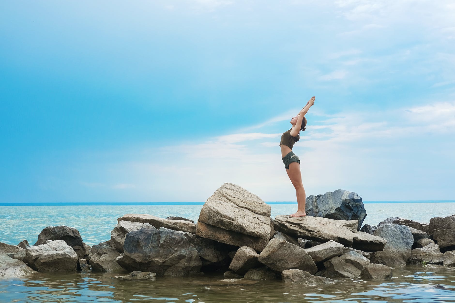 flexible woman performing yoga on stones