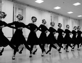 crop smiling dancers performing choreographic movement during class in hall