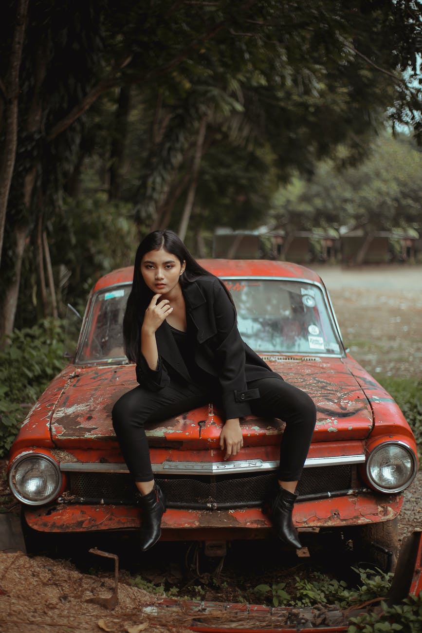 woman in black outfit sitting on red car
