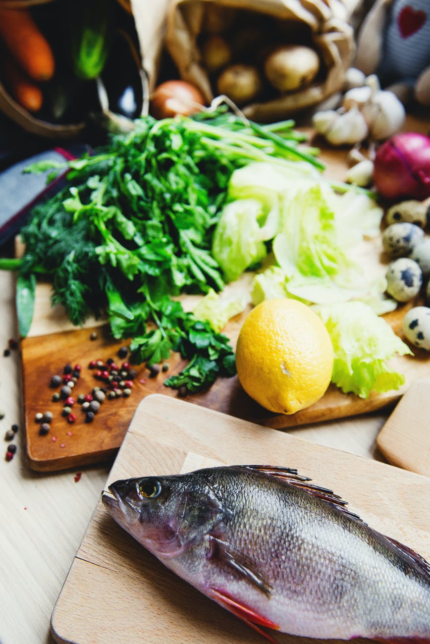 fresh fish and vegetables on cutting boards in kitchen