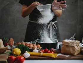 cook adding flour into baking form while preparing meal