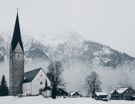 bird's-eye view photography of houses and cathedral near snow mountain