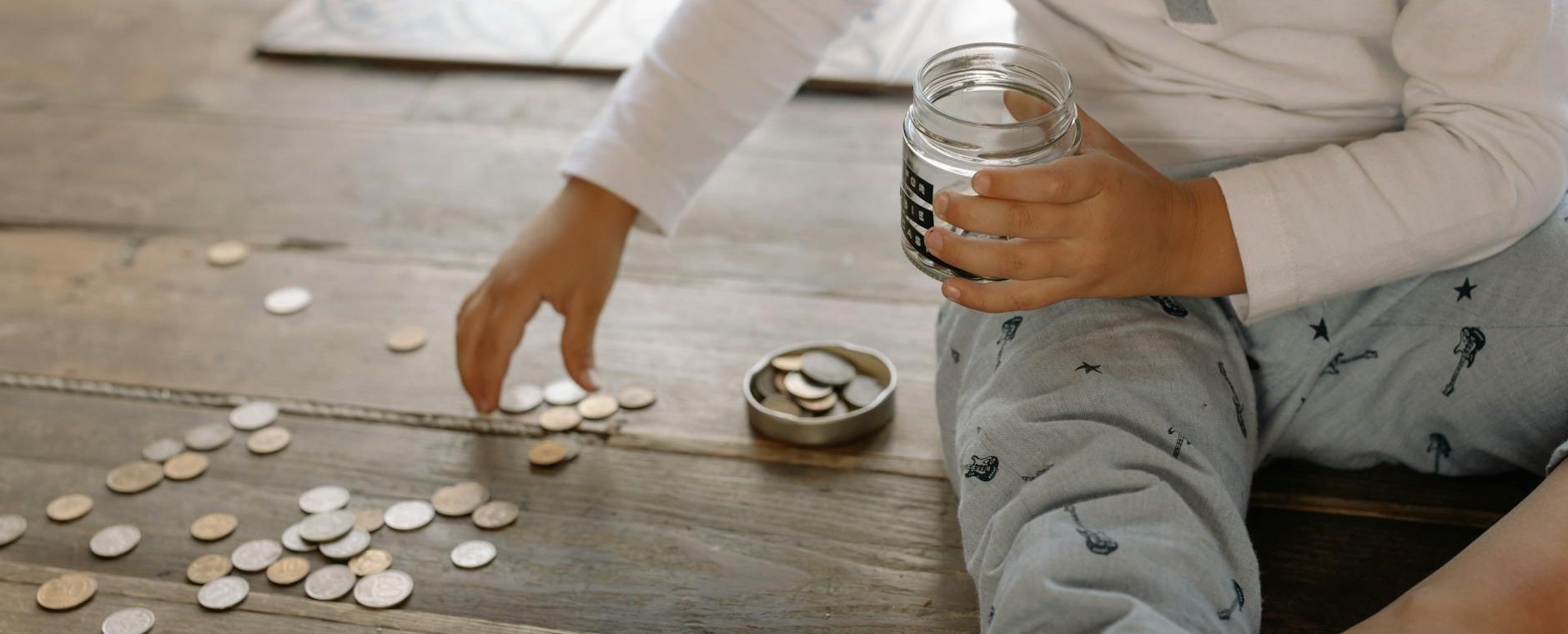 child putting coins into glass jar